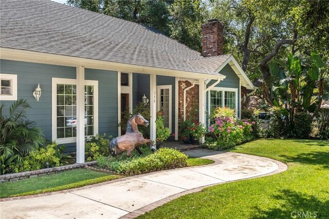 530 Bradbury Rd, Monrovia, CA 91016 - property entrance with roof with shingles, a chimney, a lawn, and covered porch
