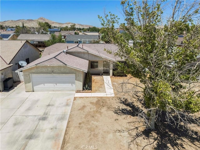2021 Buckwheat Ave, Rosamond, CA 93560 - view of front of home with concrete driveway, an attached garage, a mountain view, stucco siding, and a residential view