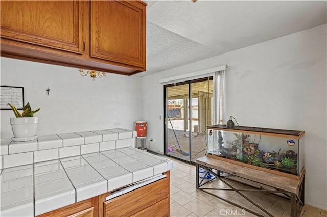 2021 Buckwheat Ave, Rosamond, CA 93560 - kitchen with tile countertops, light tile patterned floors, brown cabinets, and a textured ceiling