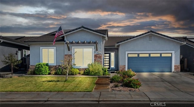 825 Spring St W, Madera, CA 93636 - ranch-style home with stucco siding, a garage, stone siding, a front lawn, and driveway