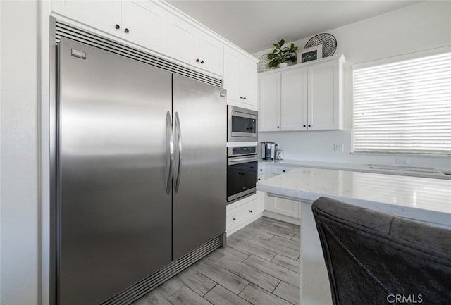 825 Spring St W, Madera, CA 93636 - kitchen featuring built in appliances, white cabinets, and light stone counters