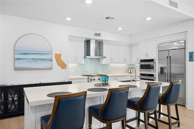 3100 Rivington, Irvine, CA 92612 - kitchen with wall chimney range hood, appliances with stainless steel finishes, light countertops, light wood finished floors, and a kitchen breakfast bar