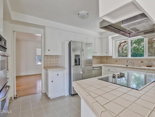 3914 Alta Vista Dr, La Canada Flintridge, CA 91011 - kitchen with wall chimney range hood, appliances with stainless steel finishes, white cabinets, tasteful backsplash, and tile countertops