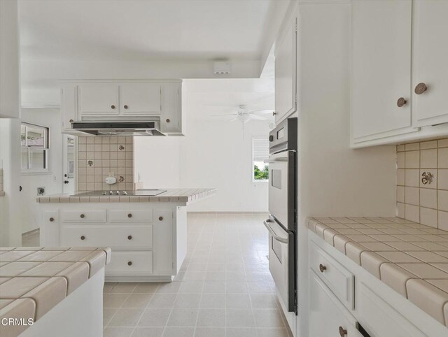 3914 Alta Vista Dr, La Canada Flintridge, CA 91011 - kitchen with tile counters, under cabinet range hood, ceiling fan, black electric cooktop, and backsplash