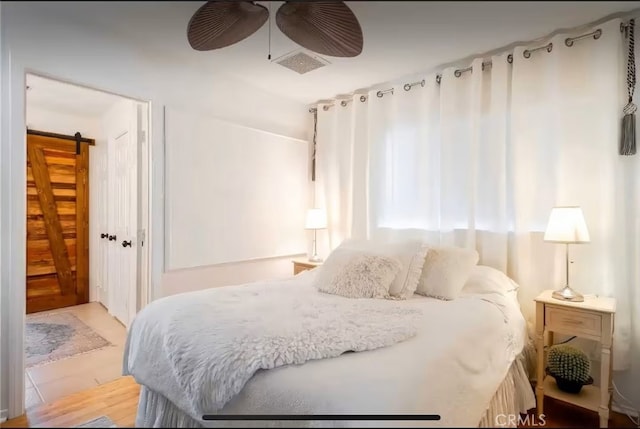 70138 Sullivan Rd Unit 29, Palms, CA 92277 - bedroom with a barn door, a ceiling fan, and wood finished floors