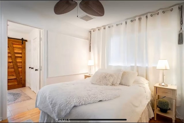 70138 Sullivan Rd Unit 29, Palms, CA 92277 - bedroom with a barn door, ceiling fan, and wood finished floors