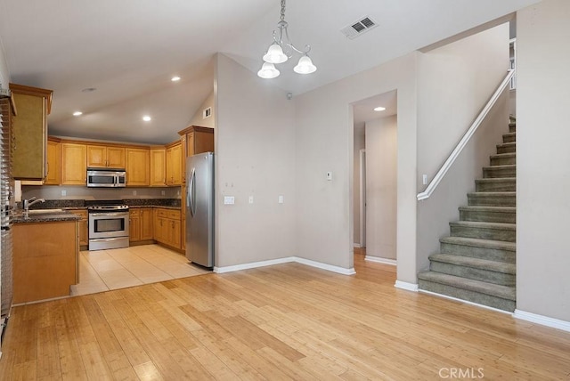 117 S Machala Pl, Rialto, CA 92376 - kitchen featuring appliances with stainless steel finishes, dark countertops, lofted ceiling, light wood finished floors, and hanging light fixtures