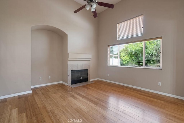 117 S Machala Pl, Rialto, CA 92376 - unfurnished living room with a high ceiling, ceiling fan, a tiled fireplace, and light wood finished floors