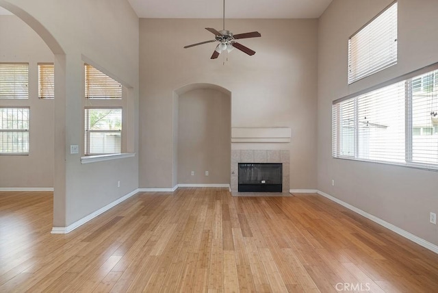 117 S Machala Pl, Rialto, CA 92376 - unfurnished living room with light wood finished floors, a towering ceiling, a fireplace, ceiling fan, and arched walkways