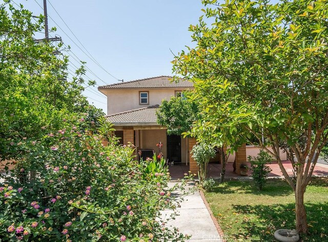 117 S Machala Pl, Rialto, CA 92376 - mediterranean / spanish-style house featuring stucco siding, a tile roof, covered porch, and a front lawn