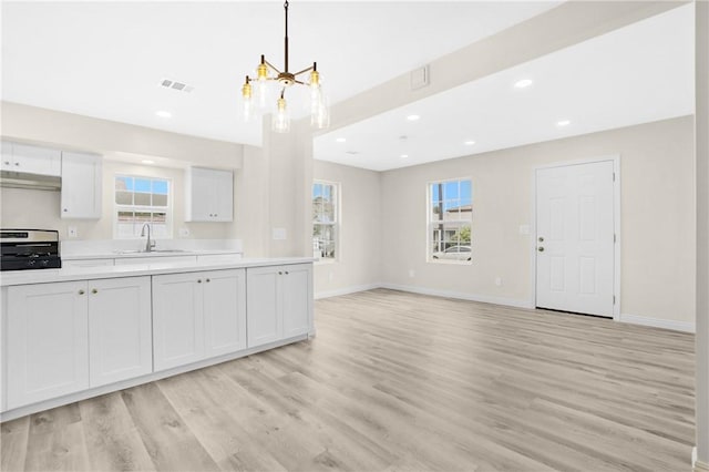 339 E 8th St, Azusa, CA 91702 - kitchen featuring under cabinet range hood, range, a chandelier, light countertops, and light wood-style floors