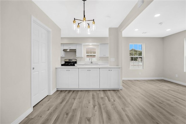 339 E 8th St, Azusa, CA 91702 - kitchen featuring a chandelier, under cabinet range hood, stainless steel gas stove, light countertops, and light wood finished floors