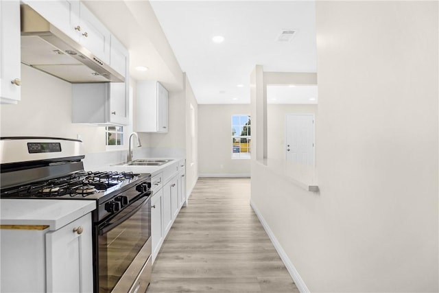 339 E 8th St, Azusa, CA 91702 - kitchen featuring gas range, under cabinet range hood, white cabinets, light wood-style floors, and plenty of natural light