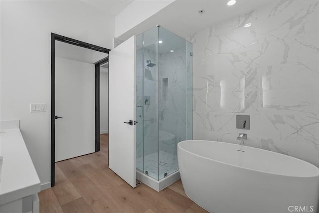 957 Figueroa Unit 318, Los Angeles, CA 90012 - bathroom featuring a soaking tub, a marble finish shower, wood finished floors, vanity, and tile walls