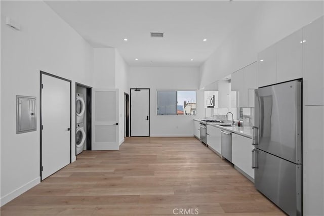 957 Figueroa Unit 318, Los Angeles, CA 90012 - kitchen featuring stainless steel appliances, stacked washer / dryer, white cabinetry, modern cabinets, and light wood-style flooring