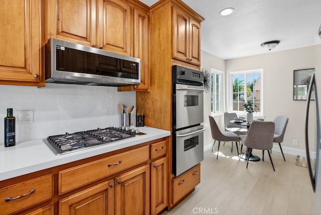 1303 E Monroe Ave, Orange, CA 92867 - kitchen featuring appliances with stainless steel finishes, decorative backsplash, light countertops, and brown cabinetry