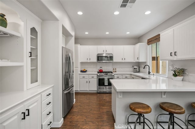 10 Cumberland Ln, Aliso Viejo, CA 92656 - kitchen with stainless steel appliances, a peninsula, decorative backsplash, dark wood-type flooring, and a kitchen bar