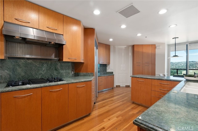 10490 Wilshire Blvd Unit 2704, Los Angeles, CA 90024 - kitchen featuring ventilation hood, black gas stovetop, light wood-style flooring, decorative backsplash, and brown cabinets
