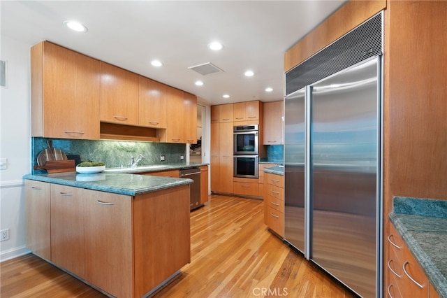 10490 Wilshire Blvd Unit 2704, Los Angeles, CA 90024 - kitchen with appliances with stainless steel finishes, light wood-style floors, a peninsula, backsplash, and recessed lighting