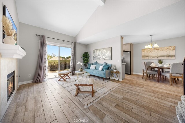 13199 Spire Cir, Chino Hills, CA 91709 - living room featuring light wood-style flooring, a chandelier, a glass covered fireplace, and high vaulted ceiling