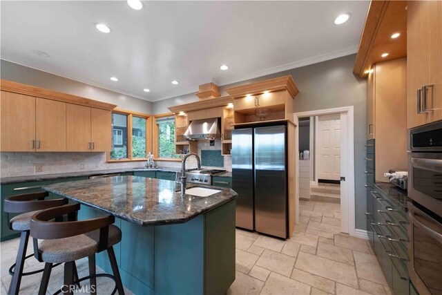 1525 Ramona Dr, Camarillo, CA 93010 - kitchen featuring stainless steel appliances, wall chimney exhaust hood, backsplash, stone tile flooring, and a center island with sink