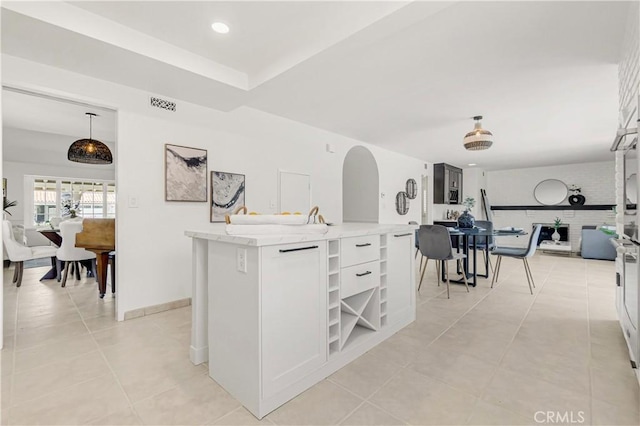 9921 Oceancrest Dr, Huntington Beach, CA 92646 - kitchen with open shelves, light tile patterned floors, open floor plan, arched walkways, and a center island with sink