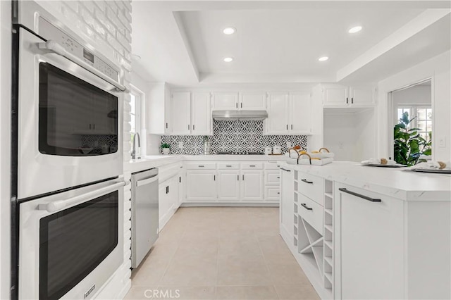9921 Oceancrest Dr, Huntington Beach, CA 92646 - kitchen featuring appliances with stainless steel finishes, a raised ceiling, decorative backsplash, recessed lighting, and white cabinetry