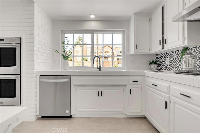 9921 Oceancrest Dr, Huntington Beach, CA 92646 - kitchen with stainless steel appliances, under cabinet range hood, white cabinets, light tile patterned floors, and backsplash