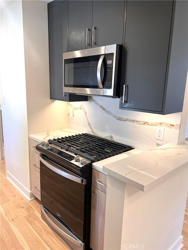 5126 Colfax Ave, Valley Village, CA 91601 - kitchen with appliances with stainless steel finishes, light wood-style floors, light stone counters, and decorative backsplash