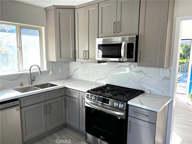 5126 Colfax Ave, Valley Village, CA 91601 - kitchen with gray cabinetry, stainless steel appliances, decorative backsplash, light stone countertops, and light wood-type flooring
