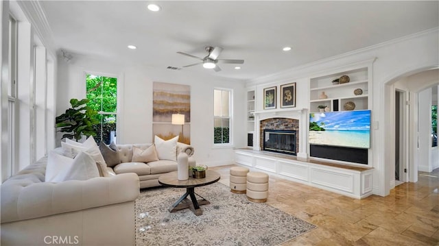 16 Bayleaf Ln, Irvine, CA 92620 - living room featuring built in features, a ceiling fan, a stone fireplace, arched walkways, and crown molding