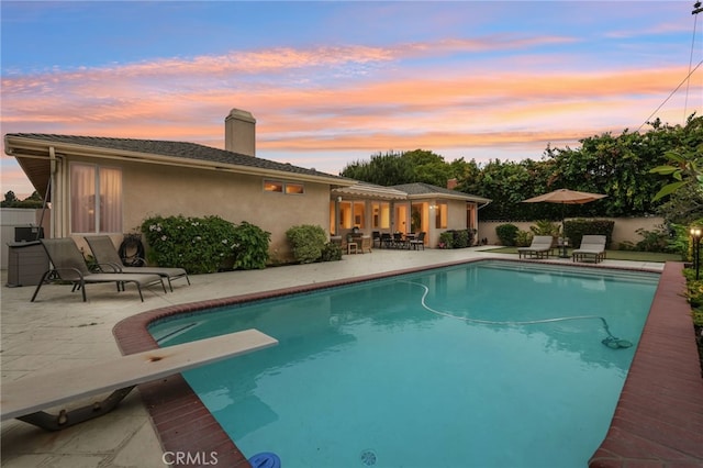 11272 Weatherby Rd, Los Alamitos, CA 90720 - pool at dusk featuring a patio area and a diving board