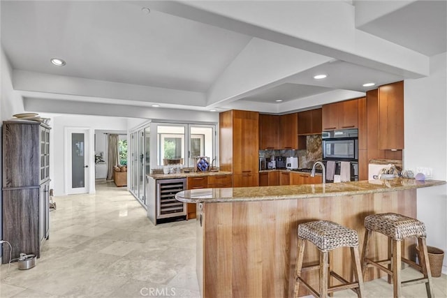 34586 Camino Capistrano Unit A, Dana Point, CA 92624 - kitchen with wine cooler, brown cabinets, light stone counters, a peninsula, and recessed lighting