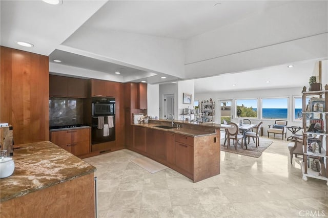 34586 Camino Capistrano Unit A, Dana Point, CA 92624 - kitchen with a peninsula, brown cabinets, recessed lighting, dark stone countertops, and modern cabinets