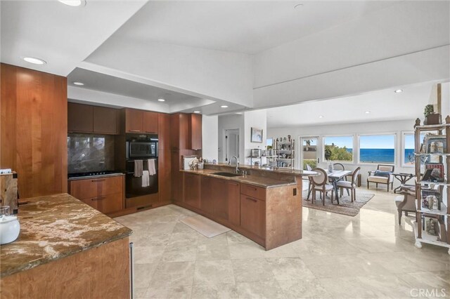 34586 Camino Capistrano Unit A, Dana Point, CA 92624 - kitchen with a peninsula, brown cabinets, recessed lighting, dark stone countertops, and modern cabinets