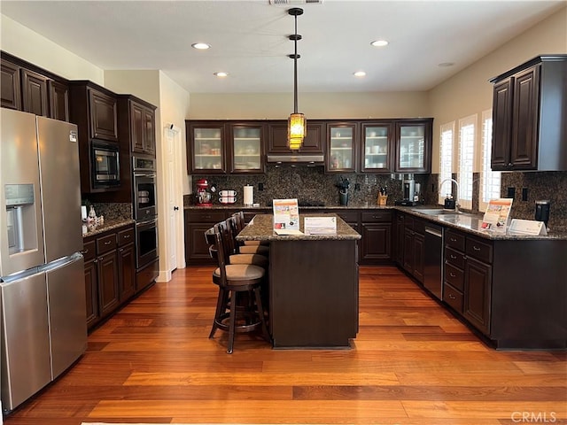 14207 Ashton Ln, Riverside, CA 92508 - kitchen with stainless steel appliances, glass insert cabinets, wood finished floors, backsplash, and a center island