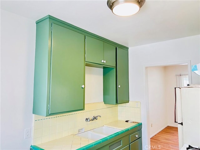 122 Elm Ave Unit 10, Long Beach, CA 90802 - kitchen featuring freestanding refrigerator, green cabinets, backsplash, and light wood-style flooring