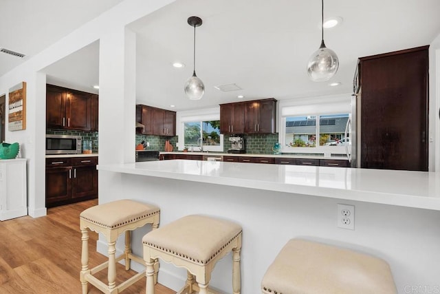 2203 Cameo Rd, Carlsbad, CA 92008 - kitchen featuring stainless steel microwave, light countertops, backsplash, a kitchen breakfast bar, and recessed lighting
