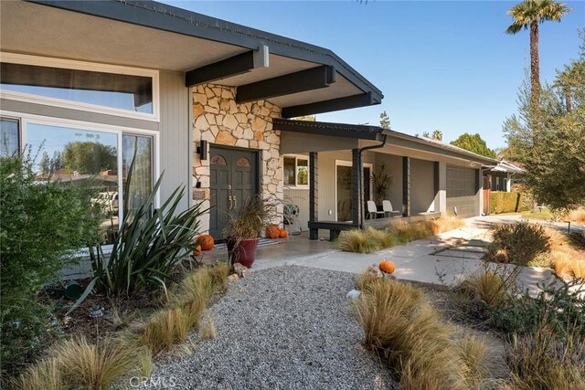 4835 Almidor Ave, Woodland Hills, CA 91364 - back of house featuring stone siding, driveway, and a garage