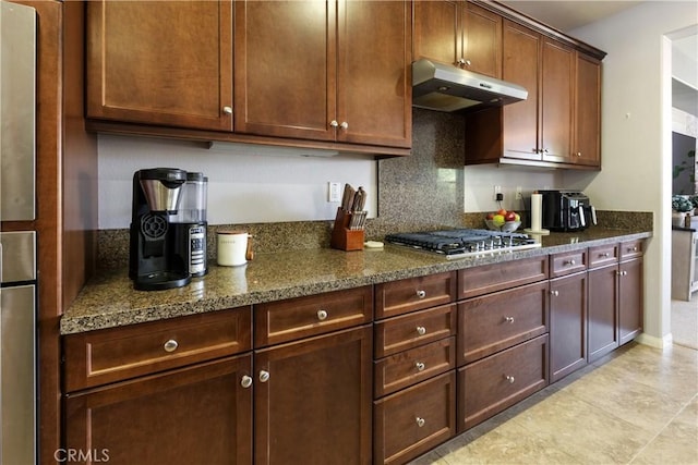 28233 Millstream Ct, Menifee, CA 92585 - kitchen with under cabinet range hood, stainless steel gas stovetop, dark stone countertops, decorative backsplash, and light tile patterned floors