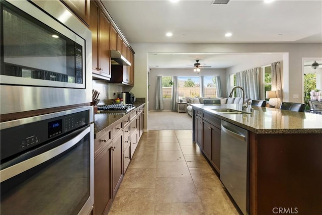 28233 Millstream Ct, Menifee, CA 92585 - kitchen with appliances with stainless steel finishes, a ceiling fan, dark stone counters, a kitchen island with sink, and recessed lighting