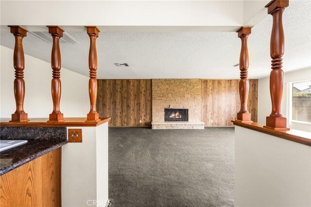 625 S Valley St, Anaheim, CA 92804 - unfurnished living room with carpet floors, wooden walls, a fireplace, and a textured ceiling