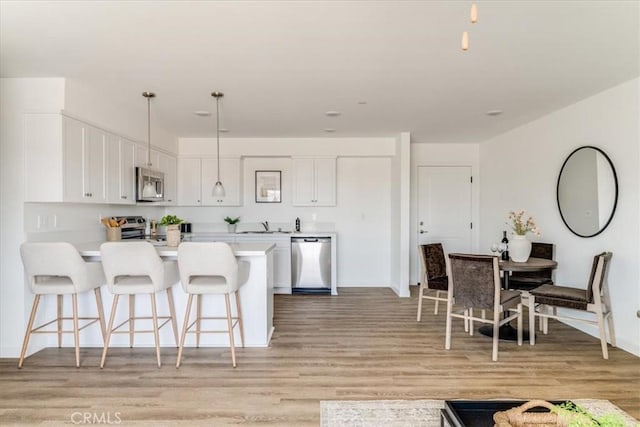 3802 Ranch House Rd Unit 102, San Luis Obispo, CA 93401 - kitchen with stainless steel appliances, a breakfast bar area, a peninsula, light wood-style flooring, and light countertops
