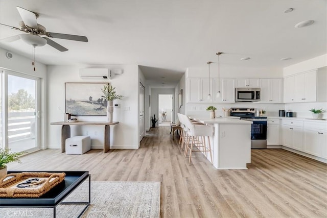 3802 Ranch House Rd Unit 102, San Luis Obispo, CA 93401 - kitchen with appliances with stainless steel finishes, light wood-style floors, a breakfast bar area, white cabinetry, and light countertops