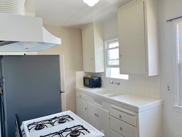 122 Elm Ave Unit 9, Long Beach, CA 90802 - kitchen with black microwave, gas range gas stove, backsplash, ventilation hood, and tile countertops