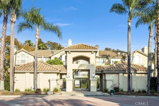 15118 Ocaso Ave, La Mirada, CA 90638 - mediterranean / spanish house featuring a gate, stucco siding, a chimney, a fenced front yard, and a tiled roof