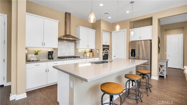 126 Luneta Ln, Rancho Mission Viejo, CA 92694 - kitchen with stainless steel appliances, wall chimney range hood, dark wood-style flooring, an island with sink, and hanging light fixtures