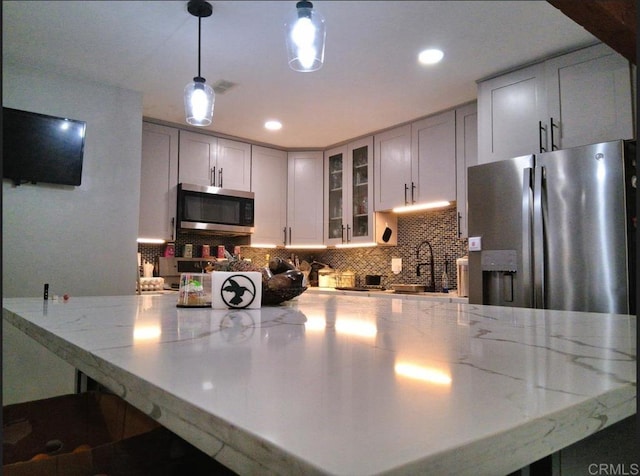 101 Lancer Ave, Oceanside, CA 92058 - kitchen with stainless steel appliances, light stone counters, glass insert cabinets, backsplash, and hanging light fixtures