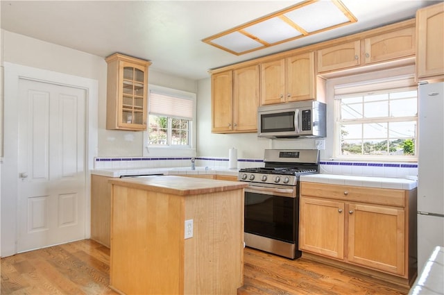 128 N Mason St, Arroyo Grande, CA 93420 - kitchen featuring stainless steel appliances, a kitchen island, light wood-type flooring, glass insert cabinets, and light brown cabinetry