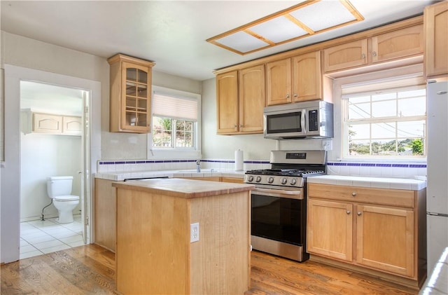128 N Mason St, Arroyo Grande, CA 93420 - kitchen featuring stainless steel appliances, light wood finished floors, glass insert cabinets, and tile countertops